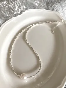 Macro detail of S925 sterling silver chain with a large lustrous white pearl pendant