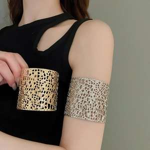 Close-up of wide hollow woven cuff bracelet in gold and silver finish on a model arm