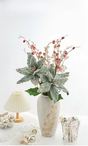 Gros plan de poinsettias verts floqués avec paillettes dorées et baies en vase