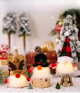 Détail de trois gnomes de Noël LED avec bois et chapeaux à carreaux sur fond de neige