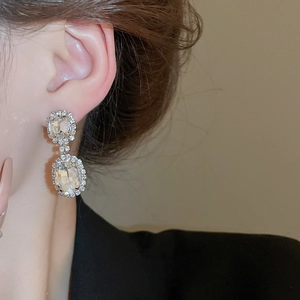 Detail of silver drop earrings featuring sparkling oval crystals on a female model