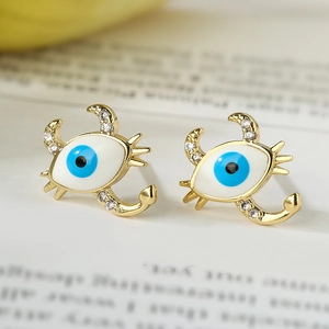 Close-up of crab-shaped 18K gold earrings with enamel evil eye and sparkling zircons