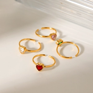 Detailed view of four-piece gold heart ring set with red, pink, green, and white stones