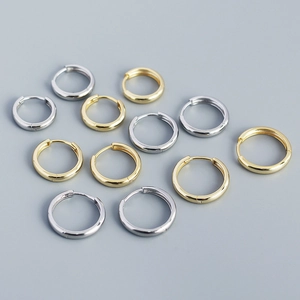 Flat lay of polished S925 sterling silver hoop earrings in gold and silver finishes