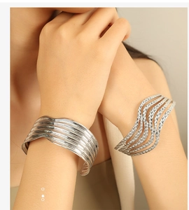 Close-up of geometric silver open cuffs with wavy and parallel textured designs on wrist