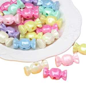 Mix of candy-shaped acrylic iridescent beads in pastel colors on a white ceramic plate