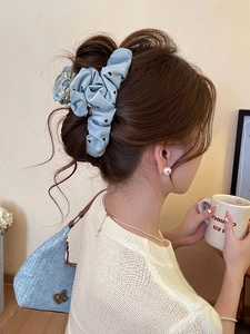 Detail of light blue heart-patterned satin hair claw clip styled on a half-up hairdo