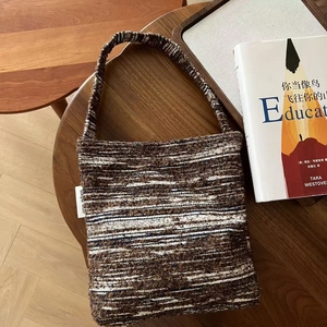 Top-down view of retro woven shoulder bag with brown and black stripes on a wooden table