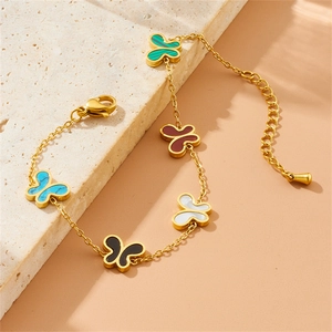 Detail of a gold bracelet featuring five colorful butterfly charms on a textured stone base