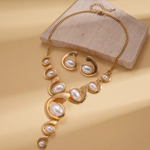Detailed set of golden necklace and earrings with large white oval pearls on stone