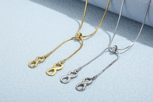 Macro detail of adjustable infinity charm on gold and silver snake chain necklaces