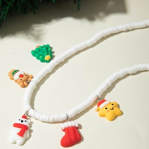 Macro view of Christmas necklace with colorful holiday charms on white Heishi beads