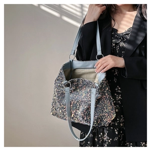 Detail of blue strap and sequined surface on a large capacity shoulder bucket bag