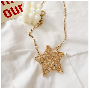 Close-up of golden star pendant featuring a delicate hollow mesh design and bead chain