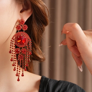 Dettaglio degli orecchini vintage con frange e strass rossi indossati da una modella