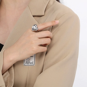 Close-up of a silver liquid heart ring with polished mirror finish on model wearing a suit