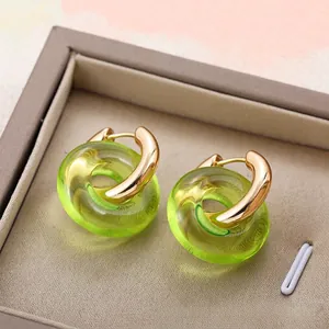 Detailed macro view of interlocking gold hoop earrings with green resin pendants