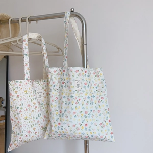 Detail shot of floral cotton tote bags hanging on a rack showing vibrant fabric patterns