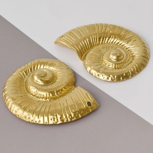 Macro detail of golden stainless steel conch pendants with textured spiral patterns