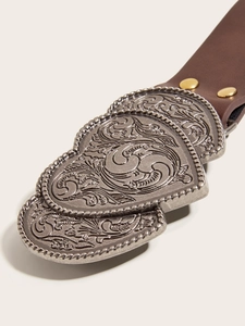 Detail of vintage heart-shaped silver buckle with embossed patterns on brown leather belt