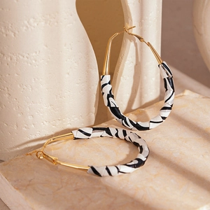 Detailed view of large gold hoops with black and white leather wrapped zebra pattern