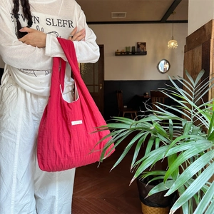 Detail of red oversized pleated canvas bag texture in a cozy cafe setting