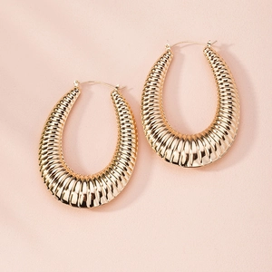 Macro shot of large golden C-shaped hoop earrings with detailed wrinkled wavy texture