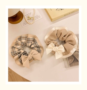 Detailed view of elegant beige plaid and waffle texture bow hair scrunchies on desk
