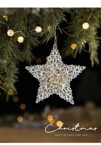 Clear acrylic star ornament with gold sequins hanging on a festive green Christmas tree