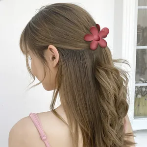 Close-up of a matte red flower hair claw clip worn on a half-up hairstyle