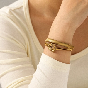Close-up of 18k gold snake chain bracelet with elegant knot detail on model's wrist