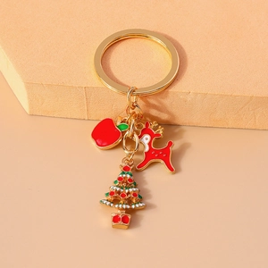 Detail of Christmas keychain with gold ring and enamel deer, tree, and apple charms