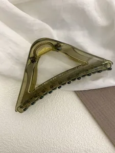 Close-up of translucent tortoise shell triangle hair claw clip with golden metal spring