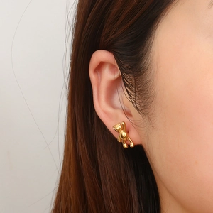 Minimalist gold-plated stainless steel bear earrings shown on a model's ear