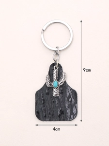 Detail showing cactus keychain with black faux leather and silver metal pendant with blue stone