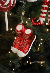 Detail of red festive high-top sneakers ornaments hanging on a Christmas tree branch
