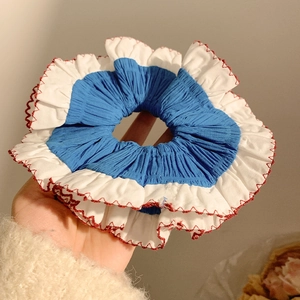 Detail of blue and white lace scrunchie with red scalloped edge and knitted texture