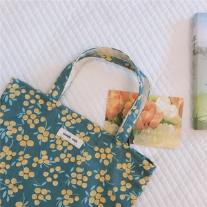 Detailed macro view of teal cotton tote bag with yellow berry print and simple wish label