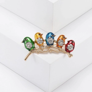 Detail view of colorful enamel birds brooch with sparkling rhinestones on a golden branch