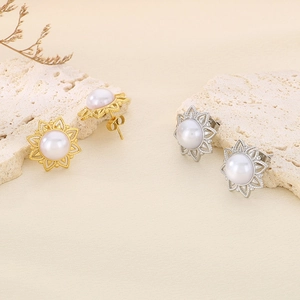 Detailed view of sunburst pearl stud earrings in gold and silver finish on a stone