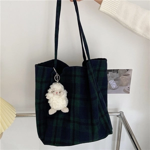Detailed view of large green plaid wool tote bag featuring a cute white sheep keychain