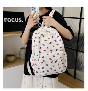 Detail of off-white corduroy backpack featuring red strawberry prints and zipper pocket