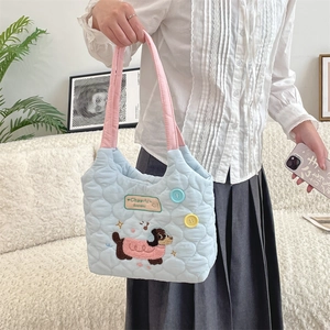 Detalle de bolso acolchado azul con bordado de perro y correas rosas en primer plano