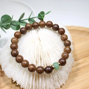 Detail of wooden beaded bracelet with green stone charm on a white decorative stand