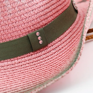 Detailed close-up of pink woven straw hat with olive ribbon and pink rhinestone accents