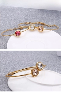 Detail of 18k gold plated bangle featuring square-cut colorful zircon and logo pendant