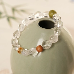 Détail du bracelet en cristal clair avec perles vertes et ambrées sur un vase décoratif
