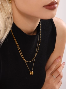 Detailed close-up of double-layered gold necklace with sparkling triple-ring pendants