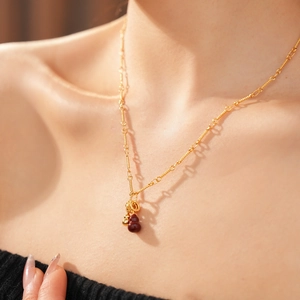 Detail of 18k gold plated necklace featuring red gourd pendant on model's neck