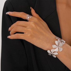 Detail of silver floral bangle and ring set with intricate radial textured petal design